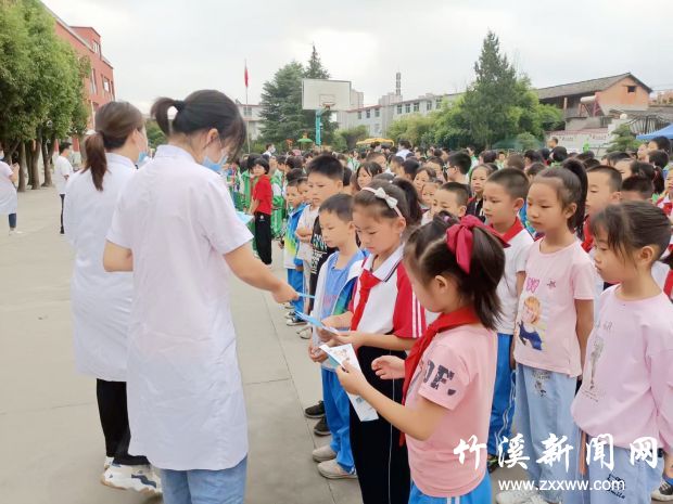 医护人员为小学生发放近视防治知识宣传手册